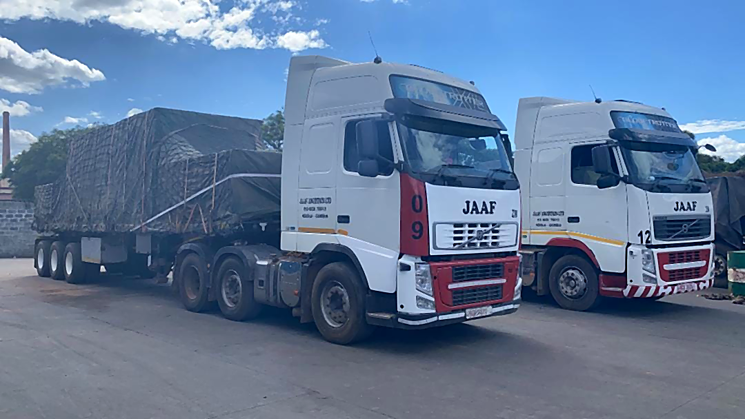 Two JAAF trucks, units 09 and 12, loaded and on the road with the JAAF door livery visible